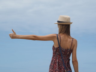 young woman in a hat hand with thumb up on blue sky