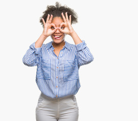 Young afro american woman over isolated background doing ok gesture like binoculars sticking tongue out, eyes looking through fingers. Crazy expression.