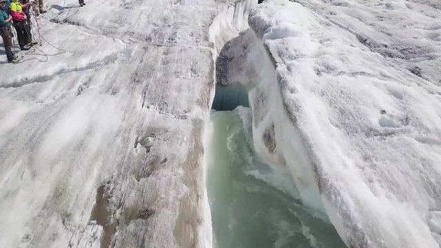Flight along a glacier stream until the water is disapears in a impressive hole.