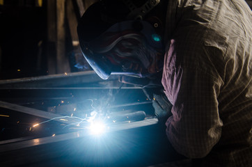 Man with mask welding iron bars