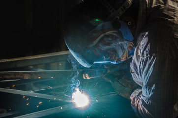 Man with mask welding iron bars