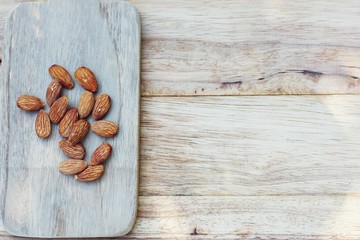 Fototapeta premium Almond nut in wooden bowl on wood board and table background, copy space