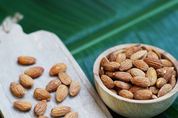 Almond nut in wooden bowl on wood board and table background, copy space