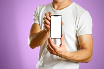 A man holding a black smartphone with a white blank screen. Smartphone with large screen. Close up....