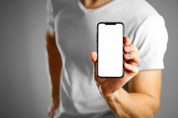 A man holding a black smartphone with a white blank screen. Smartphone with large screen. Close up....