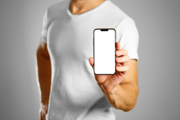 A man holding a black smartphone with a white blank screen. Smartphone with large screen. Close up....