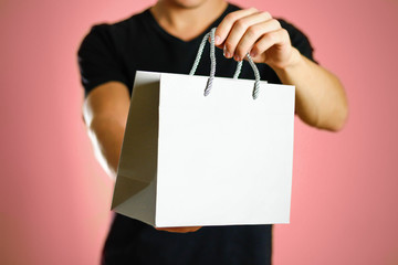 A man holding a gray gift bag. Close up. Isolated background