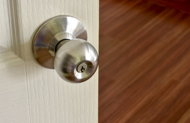 Close up of stainless metal door knob on a white painted door opening into a room.