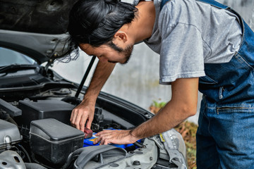 Car Repair Concept. Asian people are repairing cars on the roadside. Asian guy fixes car with confidence