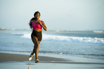 Fototapeta na wymiar young happy and attractive African American runner woman exercising on running workout at beautiful beach jogging and enjoying sunset in outdoors activity fitness concept