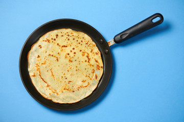 Crepe closeup, thin pancake on a frying pan, blue background