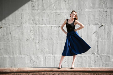 young girl posing against a concrete wall, dressed in black, hard light and shadows