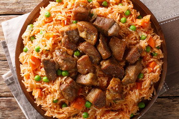 Authentic Mexican rice with green peas and carrots served with spicy pork close-up on a plate. horizontal top view
