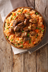 Mexican traditional food: rice cooked with tomatoes, green peas and carrots served fried pork closeup. Vertical top view