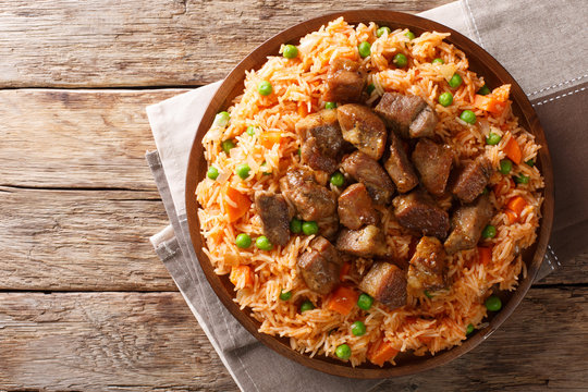 Mexican traditional food: rice cooked with tomatoes, green peas and carrots served fried pork closeup. horizontal top view