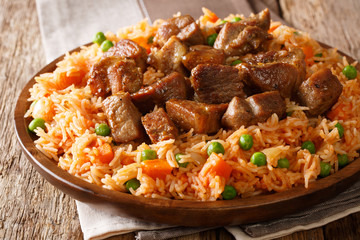 Hot Mexican rice cooked with tomatoes, green peas and carrots served fried pork close-up. horizontal