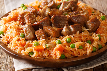 Authentic Mexican rice with green peas and carrots served with spicy pork close-up on a plate. horizontal