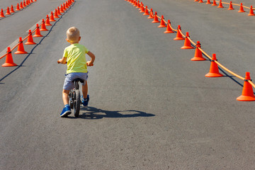 The young child without a helmet ride on the bicycle on asphalt track