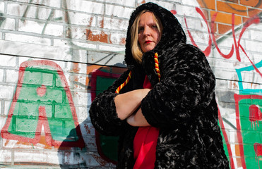 Posing von einem Model in Kunstfelljacke vor einer Graffiti Wand