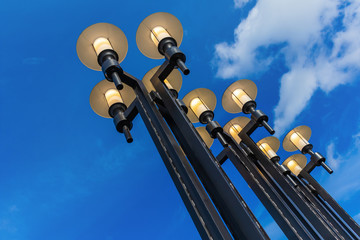 Street lights against the blue sky with clouds. Bottom-up view.