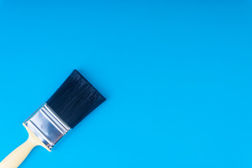 Paint brush on blue colour background with selective focus and crop fragment. Copy space conceptual