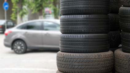 car tires in a row for sale at booth in store on the background of a gray car