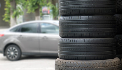 car tires in a row for sale at booth in store on the background of a gray car