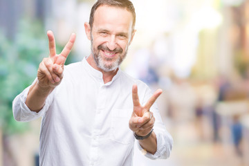 Middle age hoary senior man over isolated background smiling looking to the camera showing fingers doing victory sign. Number two.