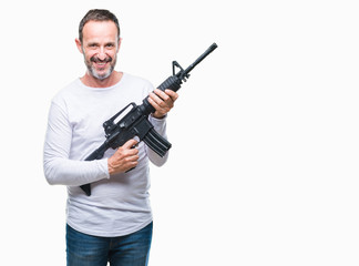 Middle age senior hoary criminal man holding gun weapon over isolated background with a happy face standing and smiling with a confident smile showing teeth
