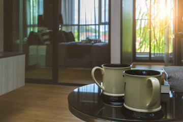 Twin white coffee or tea cup put on black table in comfortable room with sunrise lighting and copy space.