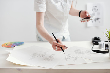 Young female designer creating sketches and infographics