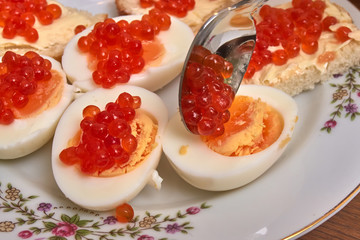 Red caviar lay on cut eggs close-up