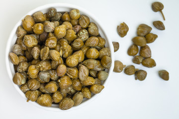 Capers with green leaves and flower on white background