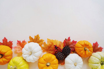 Flat lay of autumn harvest concept, pumpkins and autumn leaves on yellow background with copy space