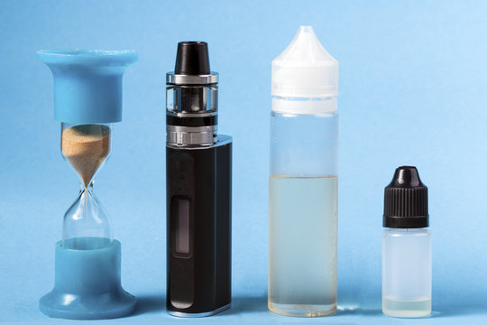 still life of vape, hourglass and refills for electronic cigarettes