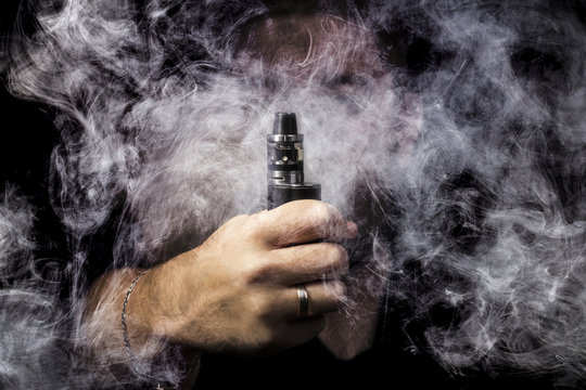 man on a black background close-up with vape hand surrounded by smoke