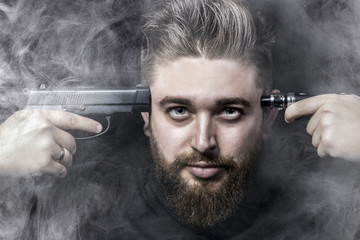 the face of a man with a pistol attached to his temple and on the other side an electronic cigarette, surrounded by smoke, smoking kills the concept, close-up background image
