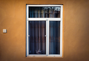 An open window with a mosquito net in the wall of the house