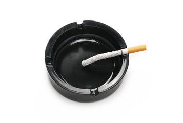 Lit cigarette in black ashtray isolated on white background
