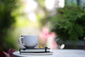 White cup with yellow flowers and notebooks