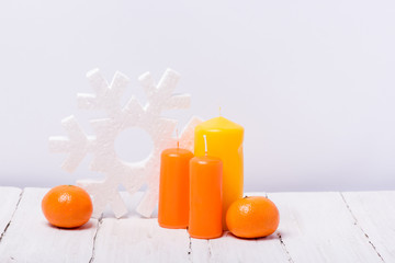 Funny mandarins and candles on a white wooden background