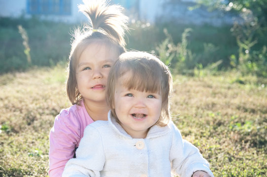 sisters portrait outdoors at sunny day. happy smiling sibling