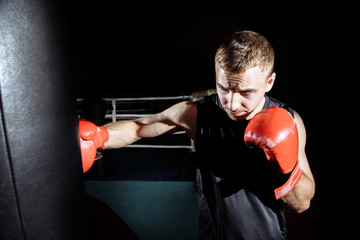 Studio shot of male boxer punching a boxing bag.