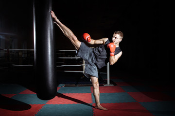 Photo of young strong sports man boxer make exercises in gym.