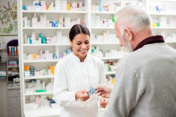 Geneeskunde, farmacie, gezondheidszorg en mensenconcept - gelukkige apotheker die medicijnen geeft aan senior man-klant
