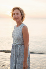 Natural portrait of a blonde woman in a dress near the sea