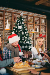 Friends having dinner at home at Christmas eve. Winter holidays concept.