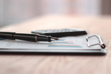 close up. pen, calculator and clipboard on wooden table. busines