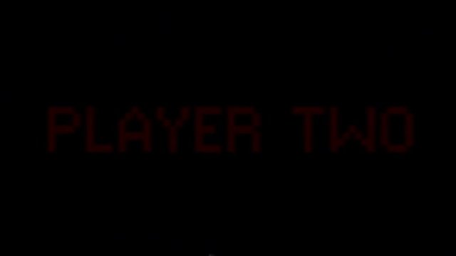 Analog VHS tape distortion: a flashing text with the words Player Two. Red on black, blocky 8-bit characters, faded color tone.
