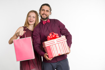 Couple, man and woman with a gift in their hands on light background.